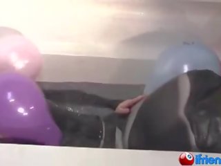 Lateksas apsirengęs jaunas ponia su balionai į a vonia