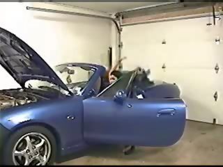 Busty brunette fucks inside a garage next to a car
